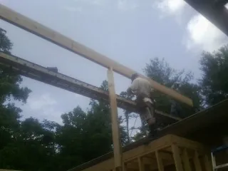 Carpenter setting a ridge beam over a new addition frame — Ice Dam Removal by Roofing Brothers in Markleton