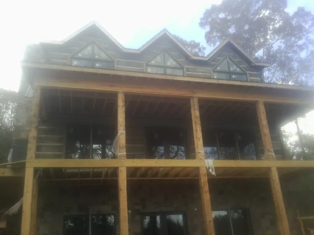 Dormers and porch framing on a large log home under construction — Roof Coating work by our crew in Markleton