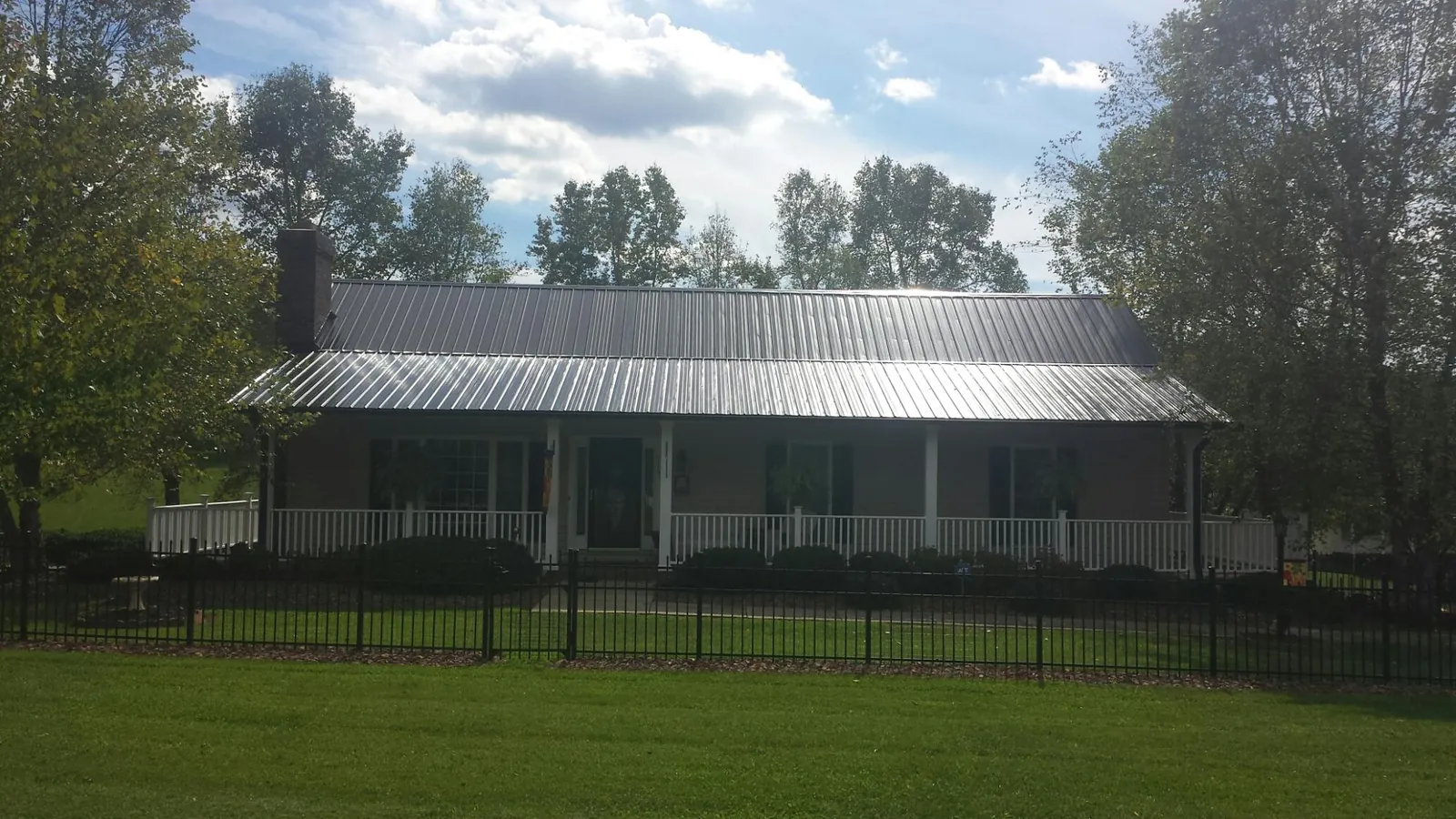 Gray metal roof on a brick ranch with a full width front porch — Gutter Guard Installation work by our crew in Markleton
