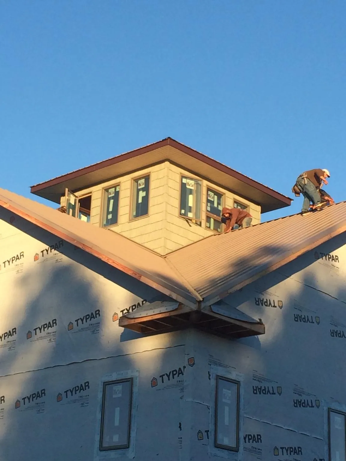 Roofers working around a rooftop cupola on a new metal roof at sunset — Roof Waterproofing in Markleton by Roofing Brothers